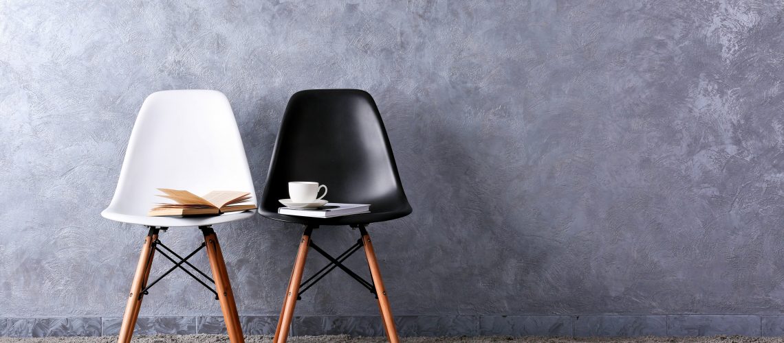 Stylische Konzeption mit weißen und schwarzen Stühlen auf grauem Hintergrund